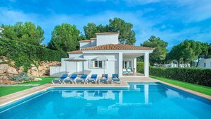 Une maison moderne dotée d’une piscine, d’un patio couvert avec des chaises longues et d’une pelouse bien entretenue.