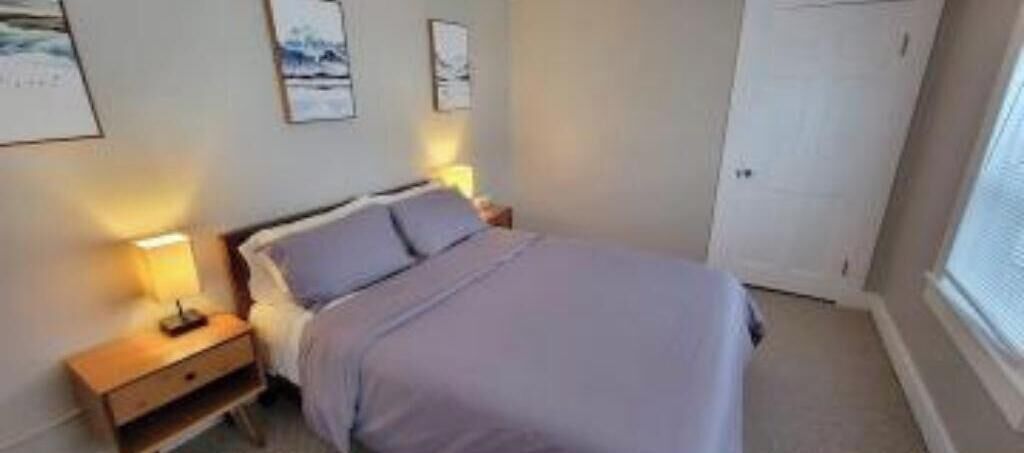 Un dormitorio con cama, mesitas de noche y cuadros en la pared.