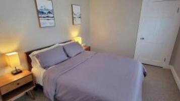 Un dormitorio con cama, mesitas de noche y cuadros en la pared.