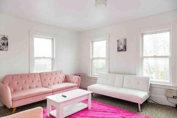A living room with two sofas, a white coffee table, and a pink rug.