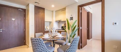 Un espace repas moderne avec une table ronde pour quatre personnes, entourée de chaises aux motifs variés.