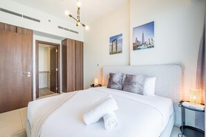 A hotel room with a large bed, a bedside table with a lamp, a wardrobe, and a door leading to a bathroom. - Enticing 2BR Apartment in Reva Residences, Business Bay by Deluxe Holiday Homes (Dubai)