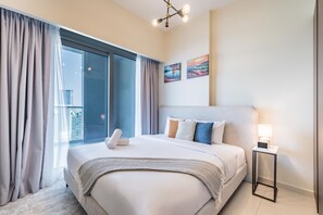 A hotel room with a bed, a nightstand, a lamp, and artwork on the wall. - Enticing 2BR Apartment in Reva Residences, Business Bay by Deluxe Holiday Homes (Dubai)