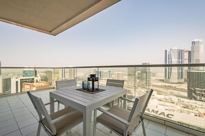 A balcony with a white table and chairs, a black lantern, and a city view. - Enticing 2BR Apartment in Reva Residences, Business Bay by Deluxe Holiday Homes (Dubai)