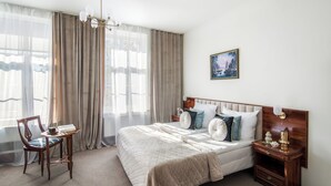 Un dormitorio con una cama grande, una mesita de noche, una silla y un cuadro en la pared.