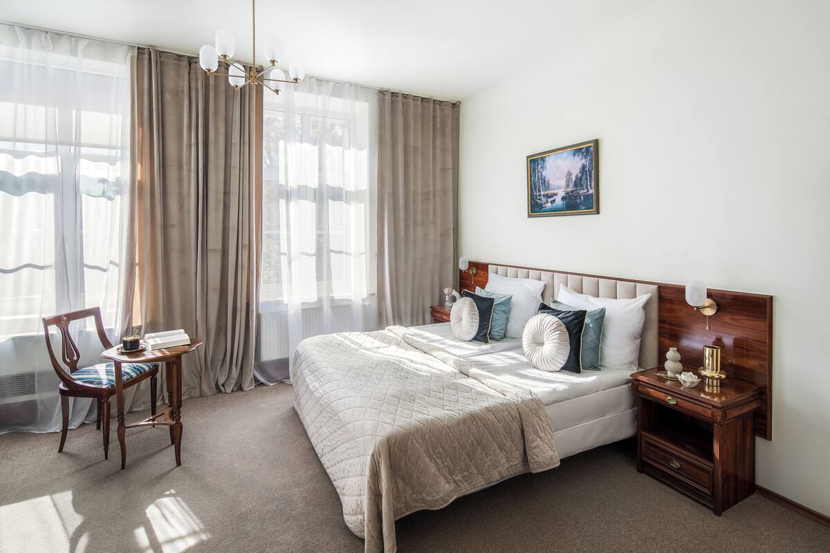 A bedroom with a large bed, a bedside table, a chair, and a painting on the wall.