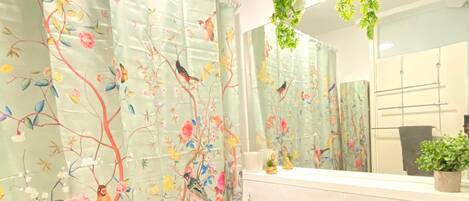 A bathroom with a white sink, toilet, and a shower curtain with floral and bird designs.