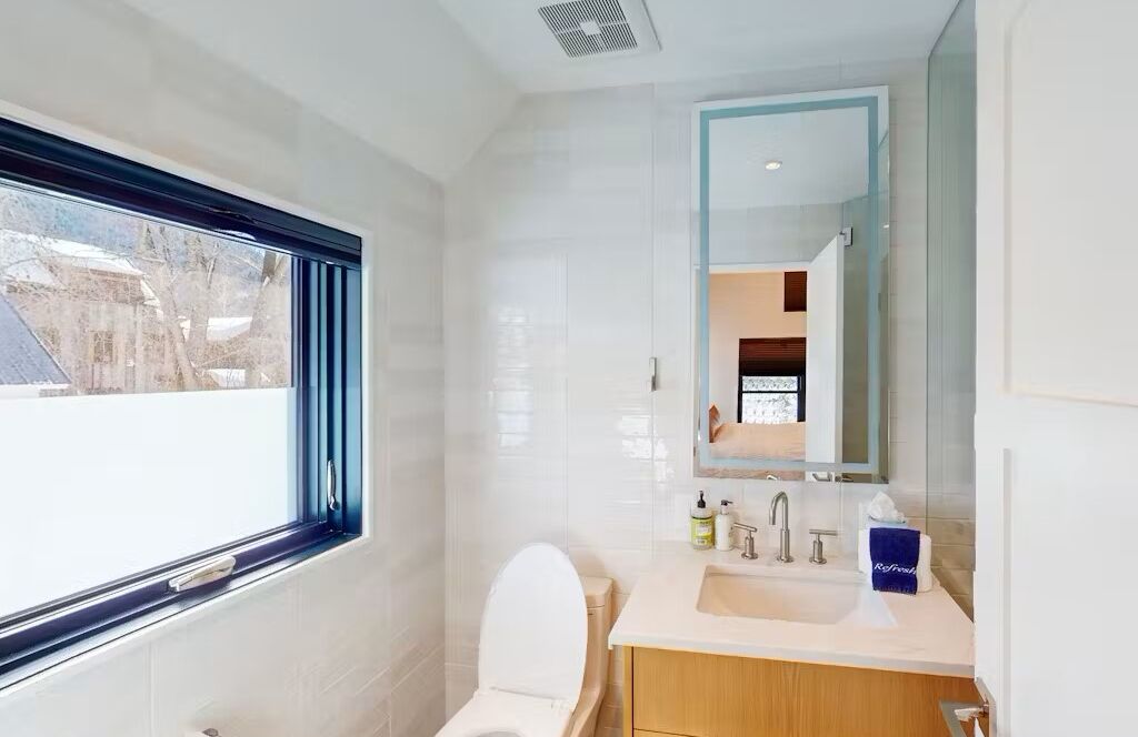 Een moderne badkamer met toilet, wastafel en spiegel.