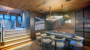 A modern dining area with a wooden ceiling, a large table with chairs, and a view of a snowy landscape through a window. - New Penthouse, Center of Town, Sauna, Deck, Fireplace, Views, Parking, Ski Room (Telluride)