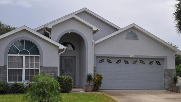 Une maison moderne à deux étages, dotée d’un garage, d’une grande fenêtre en arc de cercle et d’une pelouse bien entretenue.