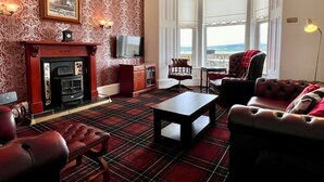 Een klassieke kamer met een open haard, een televisie en uitzicht op buiten.