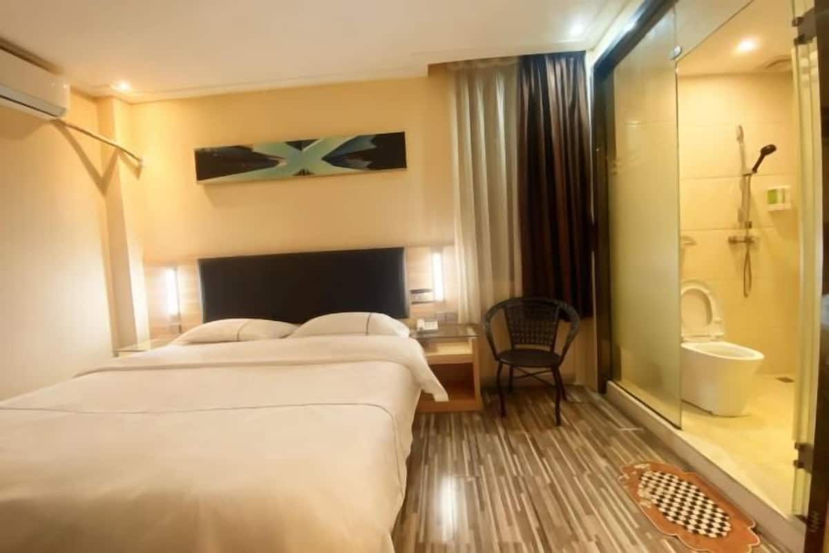 Ein Hotelzimmer mit einem Bett, einem Sessel, einer Duschkabine und einem Wandbild.