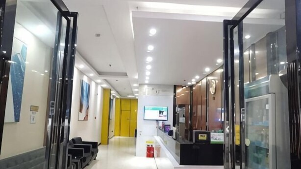 Een moderne hotel lobby met glazen deuren, een receptiebalie en een zithoek.