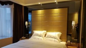 Een hotelkamer met een groot bed, een nachtkastje met een lamp en een spiegel.