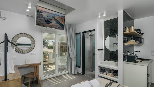 A modern bedroom with a bed, a desk, a chair, a shower, and a balcony with a view. - Orama Milos (Milos)