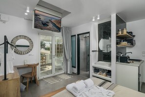 A modern bedroom with a bed, a desk, a chair, a shower, and a balcony with a view. - Orama Milos (Milos)