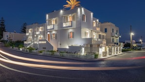 A multi-story hotel with balconies, a palm tree on the roof, and a sign reading "OZAMA". - Orama Milos (Milos)