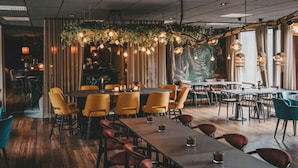 Un interno ristorante con diversi tavoli, sedie e lampadari.