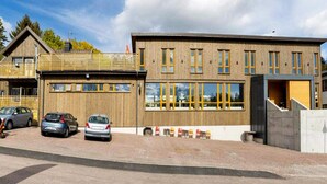 Un edificio moderno con tetto piano, ampie finestre e un'area di parcheggio con auto.