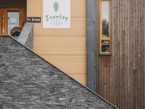 Entrada de un edificio con un cartel que dice 'Treetop SPA HANGOUT & HOTEL' y una escalera de piedra que conduce a ella.