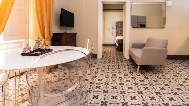 Une chambre d’hôtel équipée d’une table à manger, de chaises, d’un téléviseur, d’un miroir et d’un sol à motifs.
