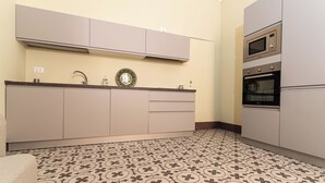 Une cuisine avec un carrelage décoratif, des placards, un four à micro-ondes et un four traditionnel.