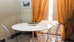 Un coin repas avec une table ronde, des chaises transparentes et un saladier posé sur la table.