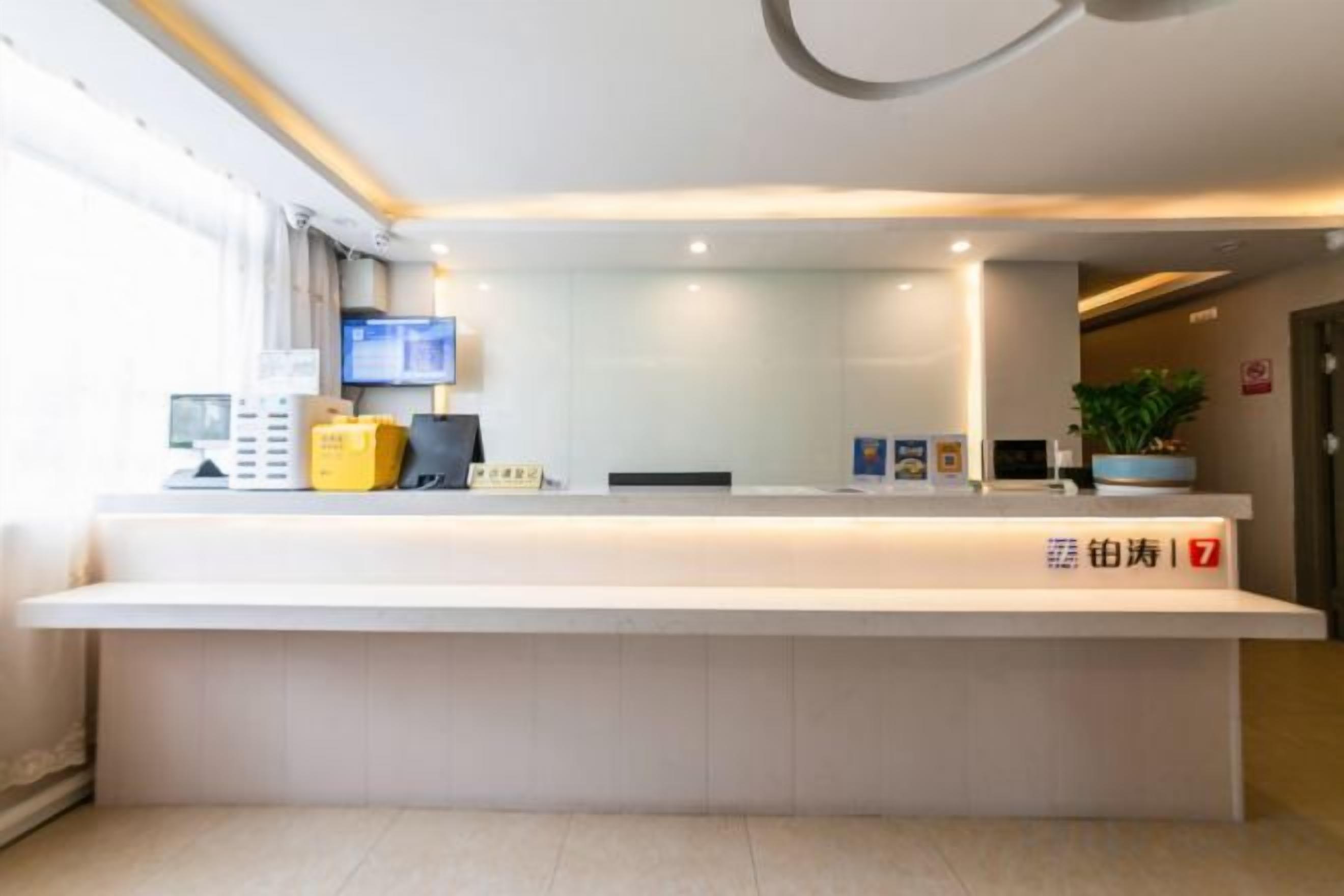 A reception desk with a flat-screen TV, a plant, and a sign with a number.