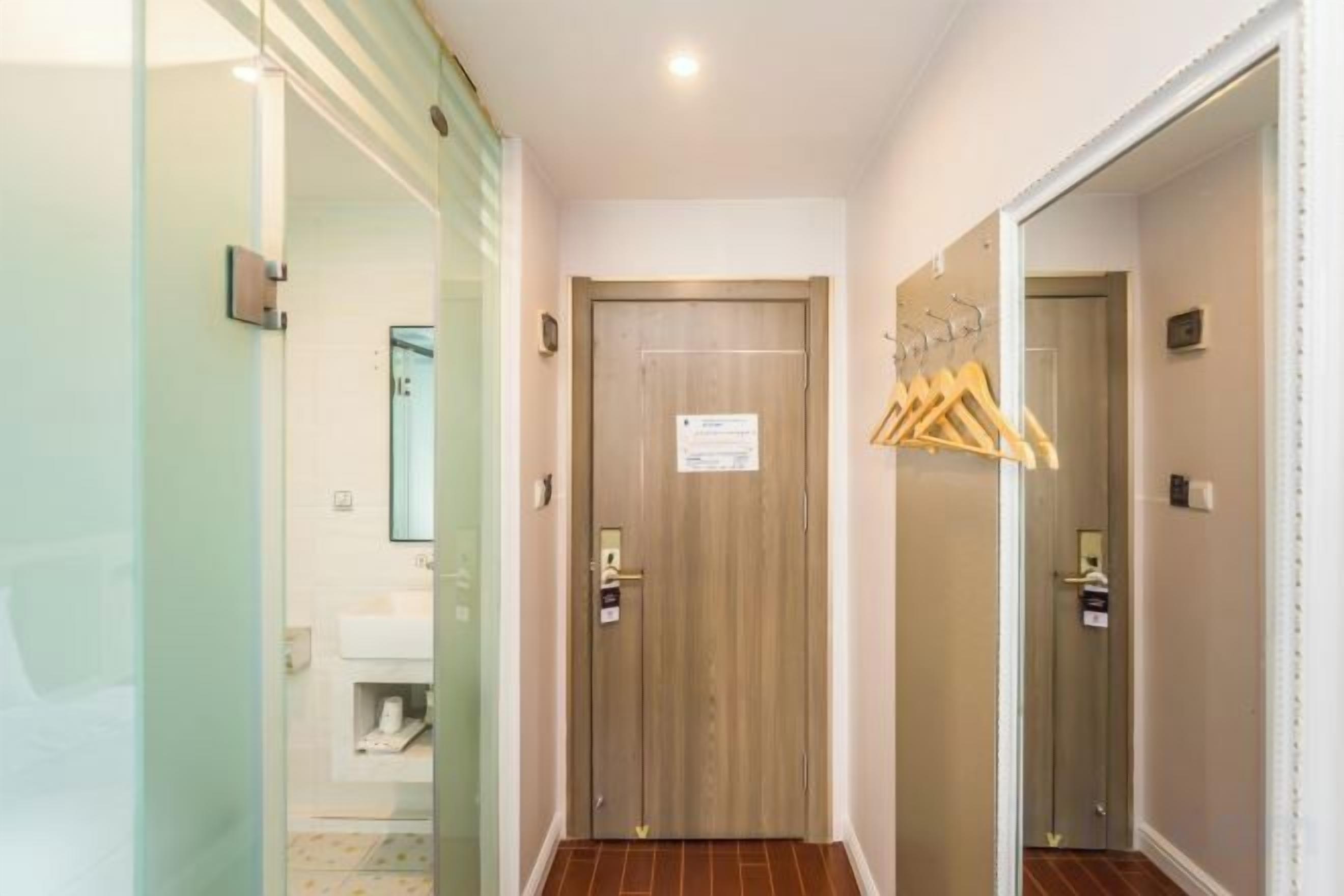 Un pasillo de hotel con una puerta de madera, un espejo y un perchero.