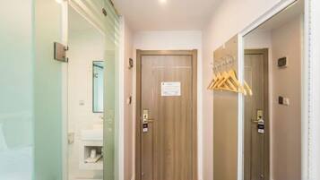 Un pasillo de hotel con una puerta de madera, un espejo y un perchero.