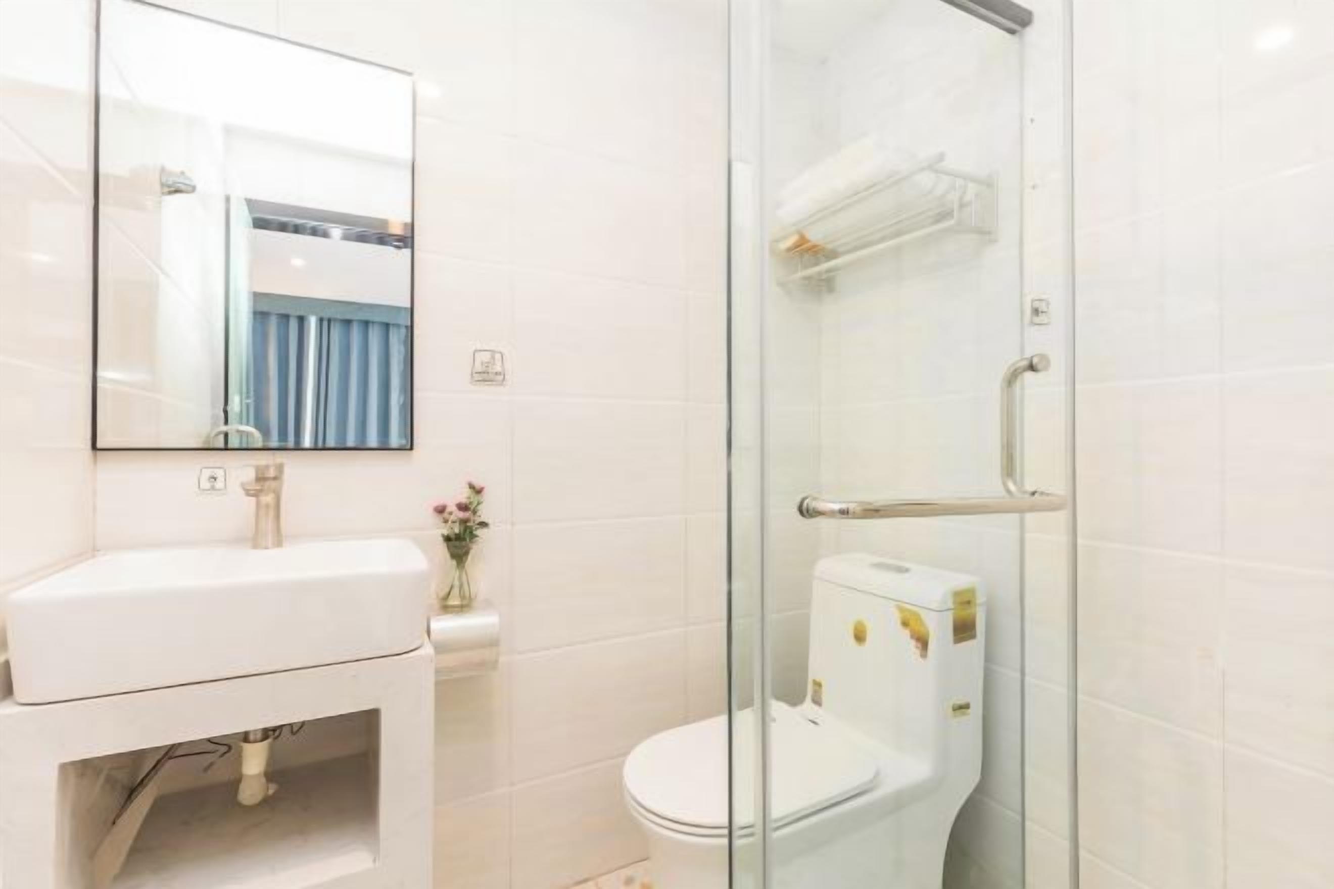 A modern bathroom with a glass shower enclosure, a white toilet, and a sink with a mirror above it.