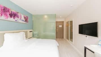 A hotel room with a bed, a TV, a painting, and a door leading to another room.