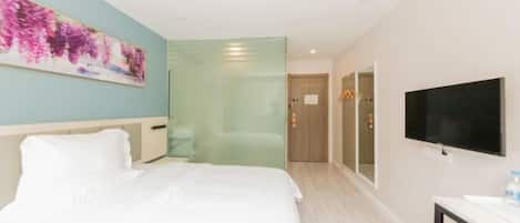 Habitación de hotel con una cama, televisor, un cuadro y una puerta que da a otra habitación.