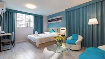 Une chambre d’hôtel comprenant un lit, un bureau, une chaise, une table basse en verre et une lampe.