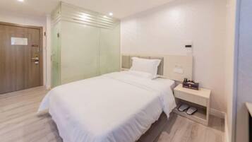 A bedroom with a bed, a nightstand, a shoe rack, and a door.