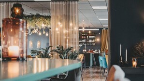 Eine moderne Bar mit einer Holztheke, Sitzplätzen und einer Wand aus Pflanzen und dekorativer Beleuchtung.