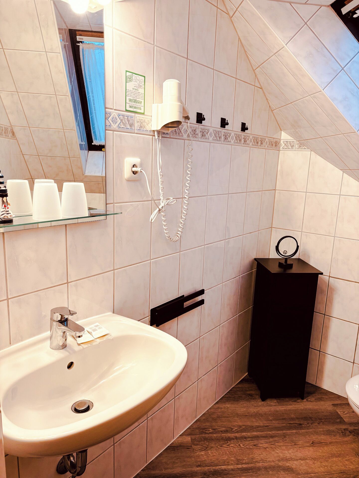 A bathroom with a white sink, a mirror, a shower, and a toilet.