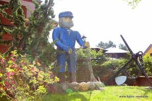 En havefigur forestiller en person i blå uniform med en lanterne.