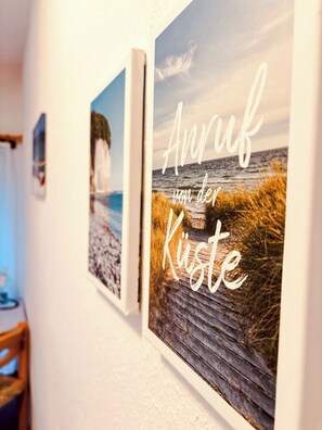 Two framed pictures on a wall, one depicting a beach scene and the other featuring text in a foreign language. - Hotel Nordwind Lohme (Lohme)