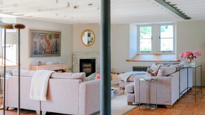 Una sala de estar con chimenea, sofás, una mesa de centro y un cuadro grande en la pared.