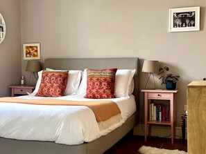 Quarto bem arrumado com cama, mesas de cabeceira, um criado-mudo e uma estante de livros.