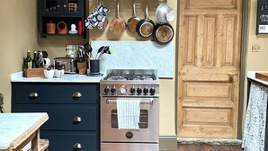 Une cuisine équipée d’une cuisinière, de placards et de casseroles suspendues.