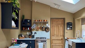 Une cuisine compacte dotée d’un four encastré, d’une porte en bois et d’un petit coin repas avec une table et des chaises.