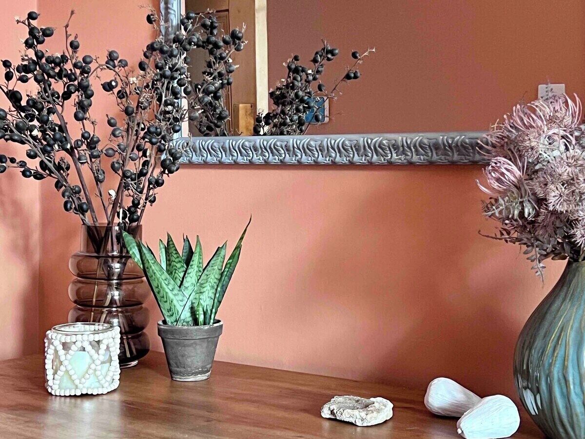 A wooden table with a potted plant, a decorative vase, and a mirror.