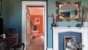 A hallway with a fireplace, a mirror, and a staircase leading to another room.