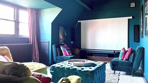 A cozy room with a large screen, comfortable seating, and a view of the outdoors. - Edwardian Town House - Garden & Cinema (Somerset)