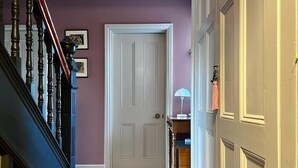 A hallway with a wooden staircase, a closed door, and a lamp on a table. - Edwardian Town House - Garden & Cinema (Somerset)