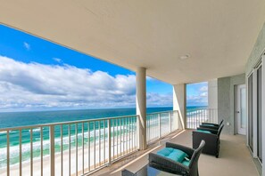 A balcony with a view of the ocean and beach, furnished with wicker chairs and a small table. - Long Beach Resort 2-1206 (Panama City Beach)