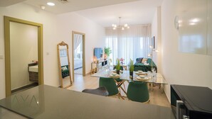Ein modernes Wohnzimmer mit einem Glastisch, grünen Stühlen, einer Couch und einem Fernseher.