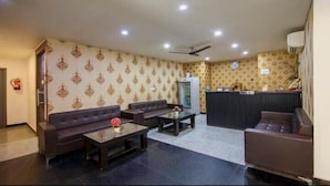 A hotel lobby with patterned wallpaper, dark sofas, a reception desk, and a ceiling fan. - hotel noida express (Noida)